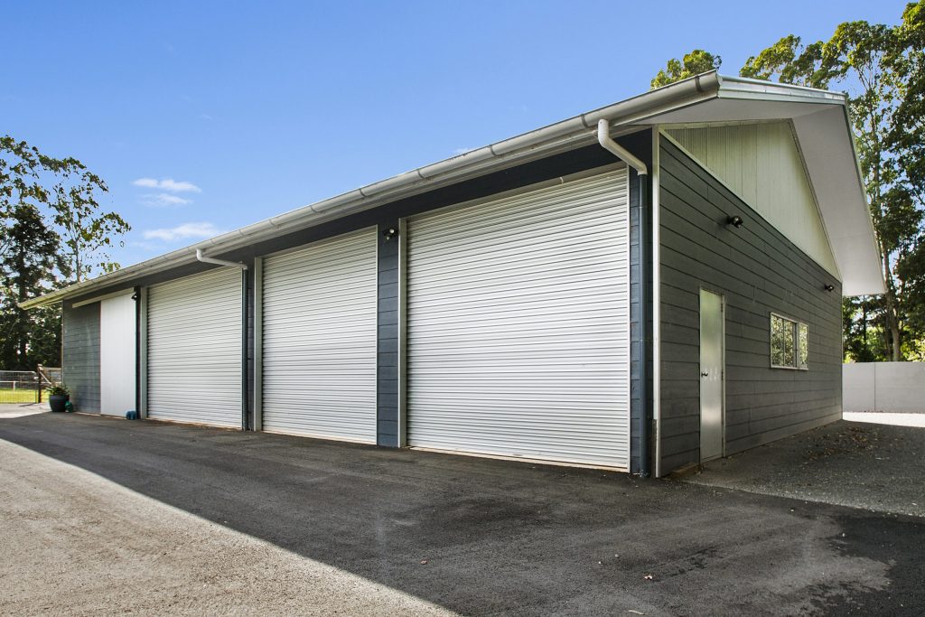 sunshine coast shed with three large roller doors blue and white