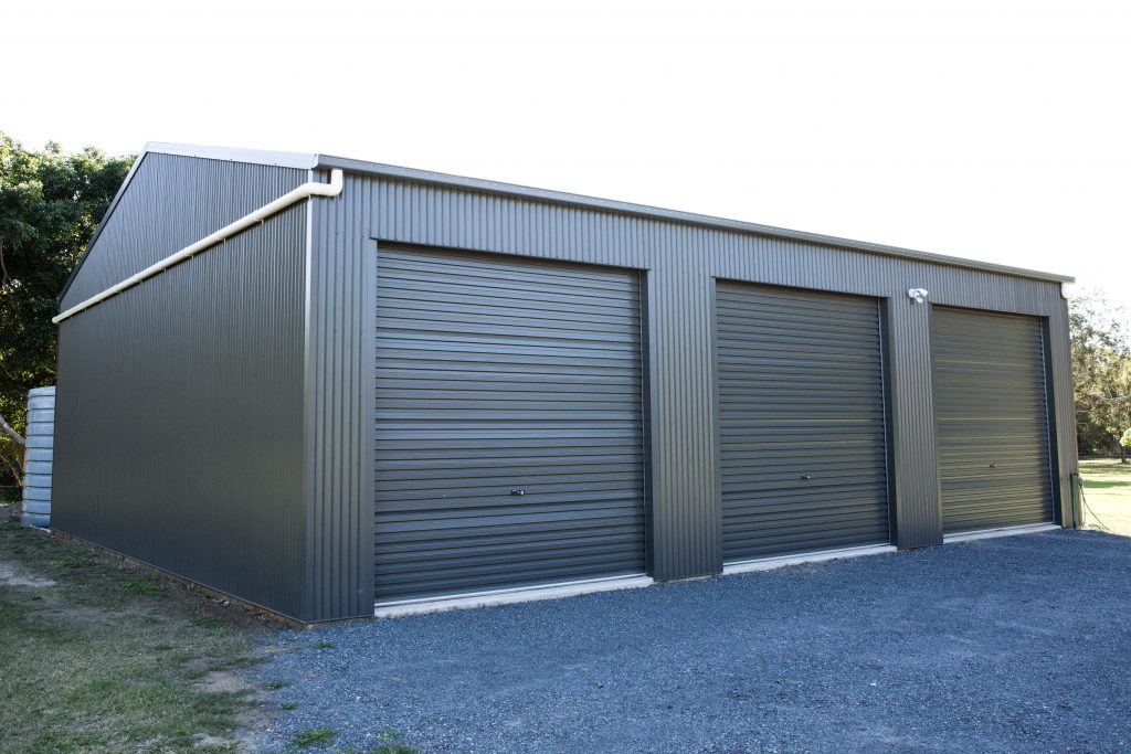 dark grey large rural shed with three roller doors